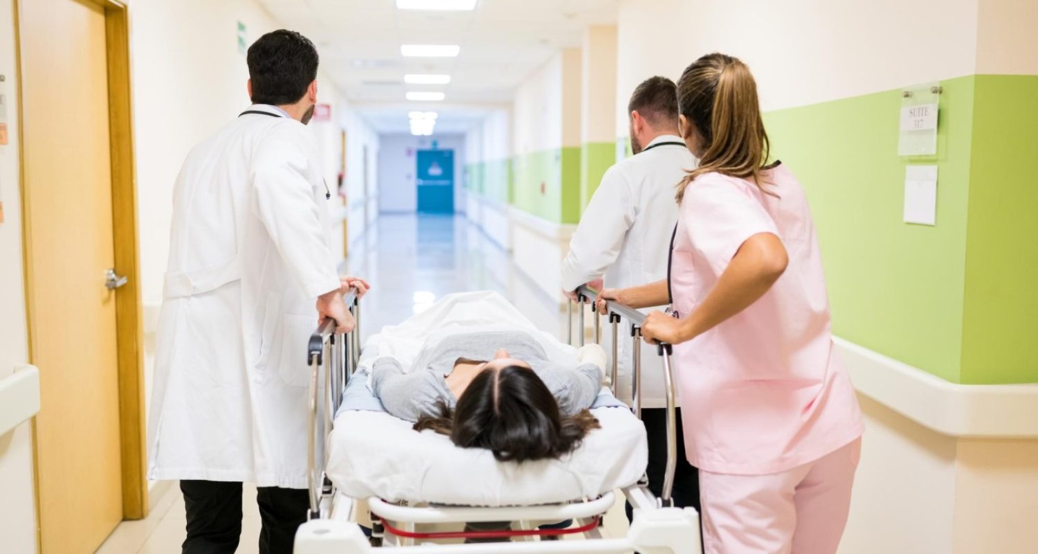 doctors-nurse-pushing-female-patient-stretcher-corridor-hospital (1)
